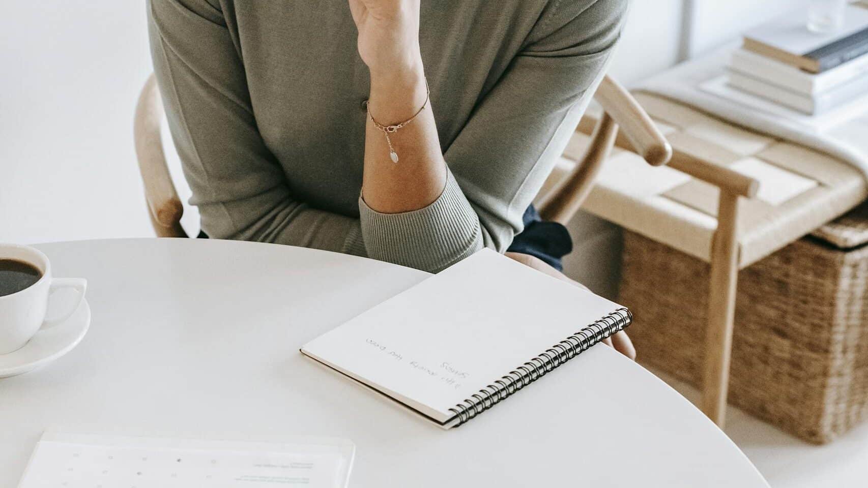 High angle crop professional female psychotherapist with pen and notepad listening attentively to client during psychotherapy session in light studio